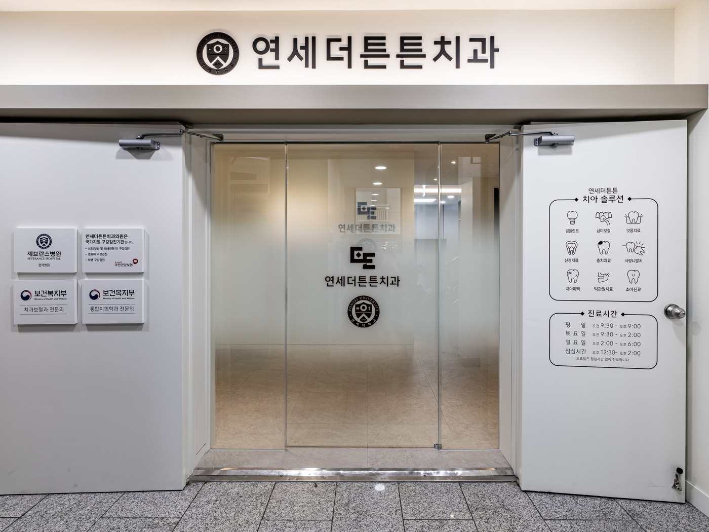 연세더튼튼치과 2층 출입구 실제 사진 — 연세대학교 엠블럼 간판과 보건복지부 전문의 명판